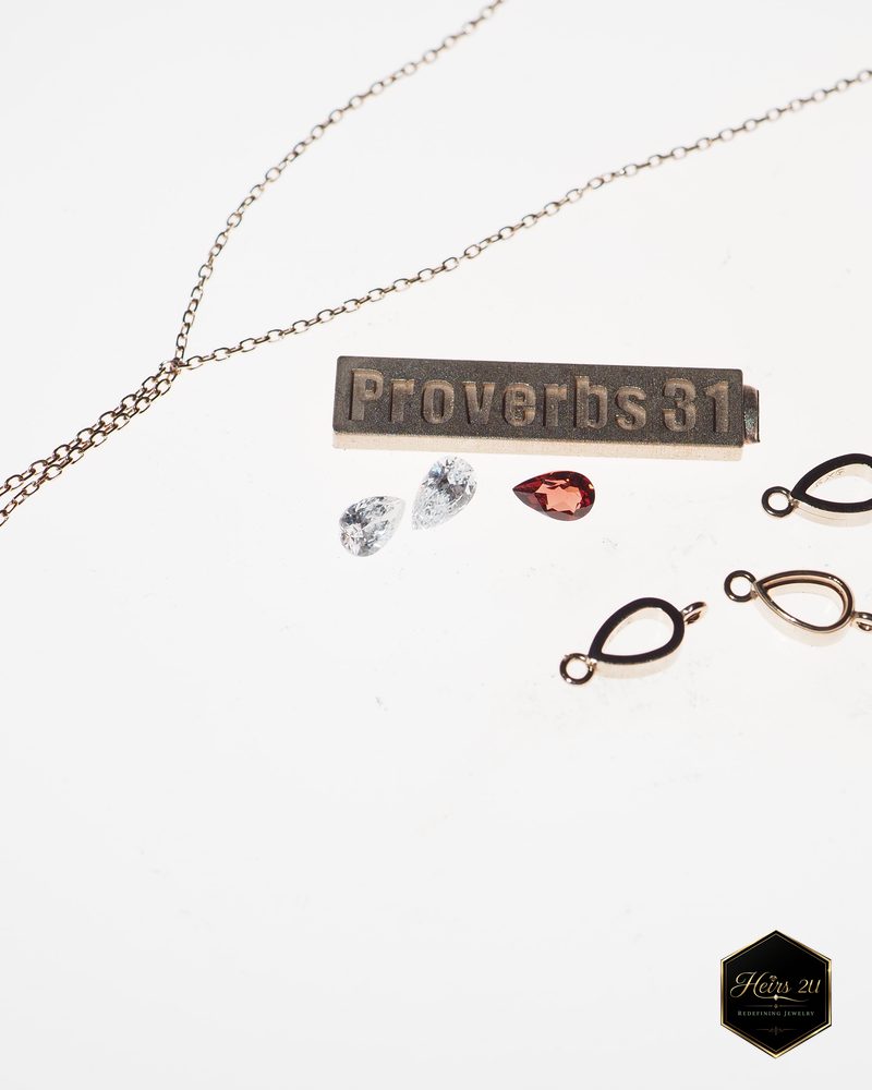 The parts of the Proverbs 31 pendant before assembly: the engraved bar, loose pear and round stones, bezels and chain