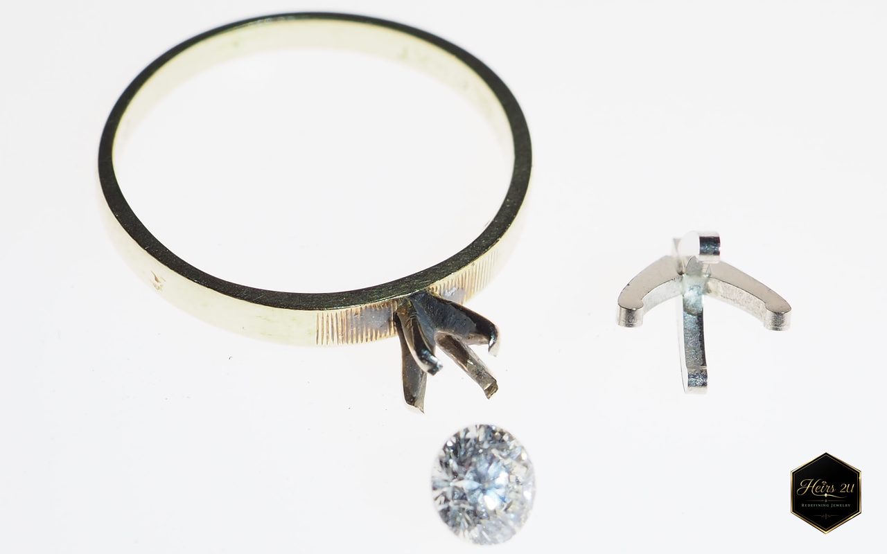 A solitaire ring before assembly: the band with its prong head, a loose round stone, and a spare setting
