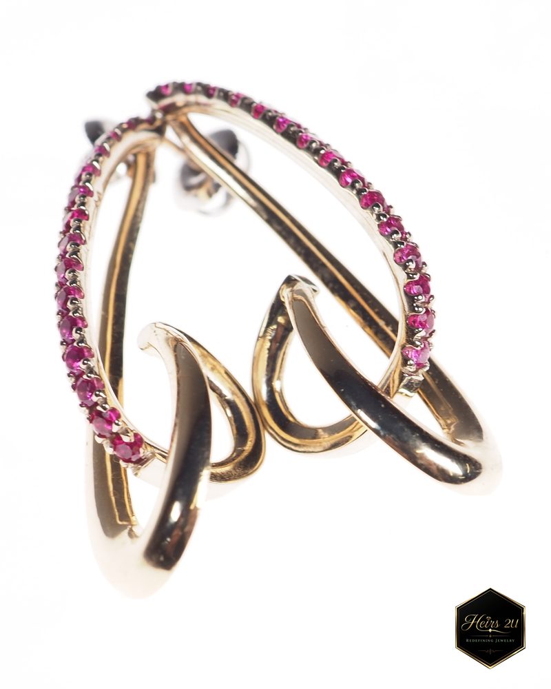 The Jacque Earring photographed: an interlocking gold ear climber with a curved band of small red stones