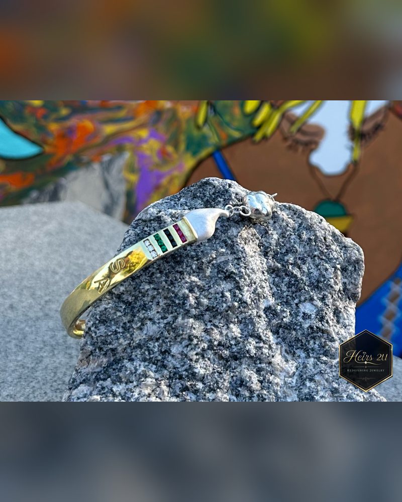 The Curved Paintbrush Bracelet photographed resting on stone in front of a painted mural