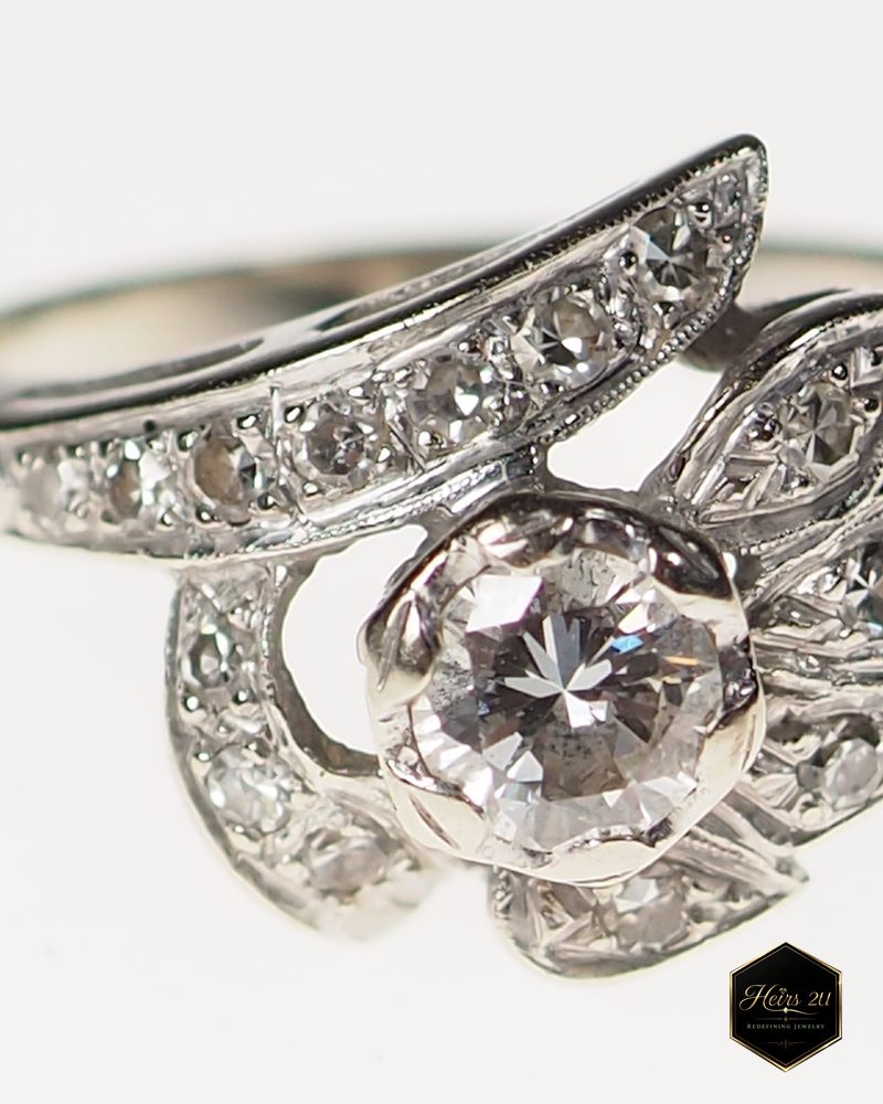 A white-metal ring with a round diamond centre set inside petals of smaller diamonds