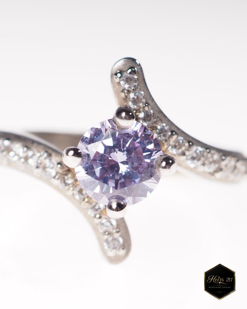 A bypass ring with a round lavender centre stone and diamond-set shoulders sweeping past each other