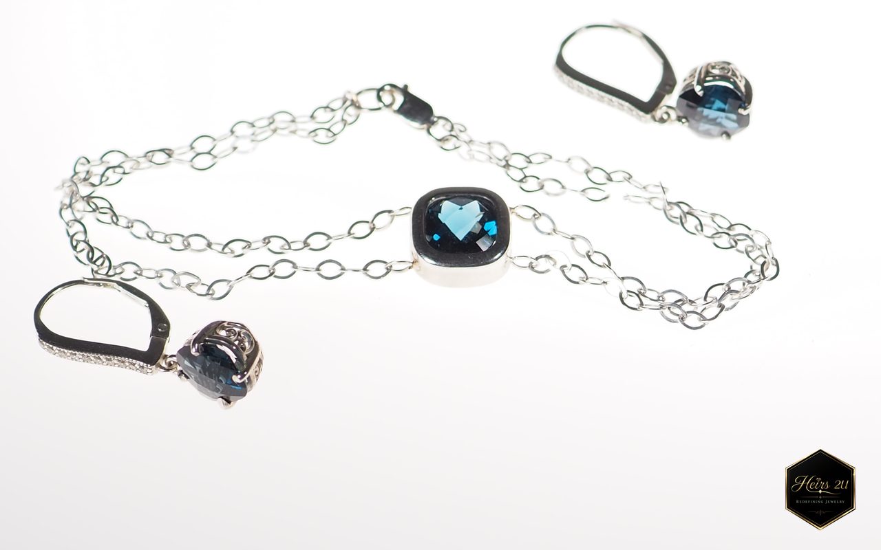 A fine chain bracelet with a cushion-cut blue stone at the centre, beside matching blue-stone drop earrings
