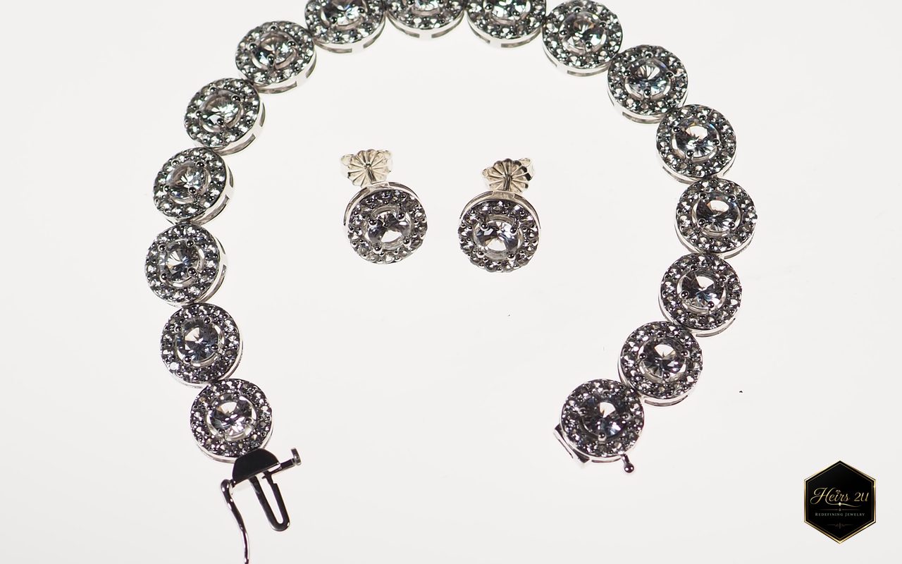 A bracelet of round halo-set stones laid in an arc around a matching pair of halo stud earrings