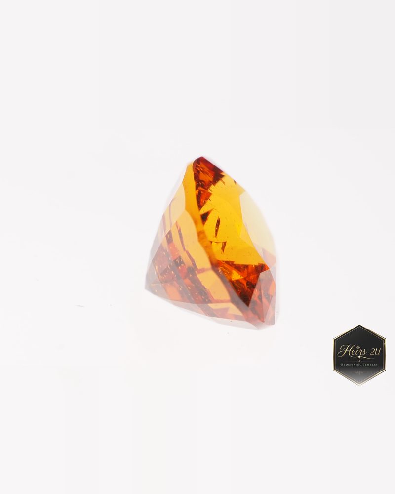 An orange Nigerian garnet seen from the side, showing its pavilion facets