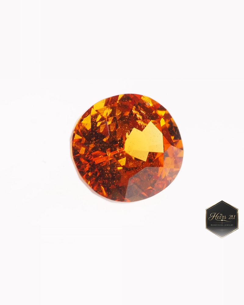 A round faceted orange Nigerian garnet photographed on white